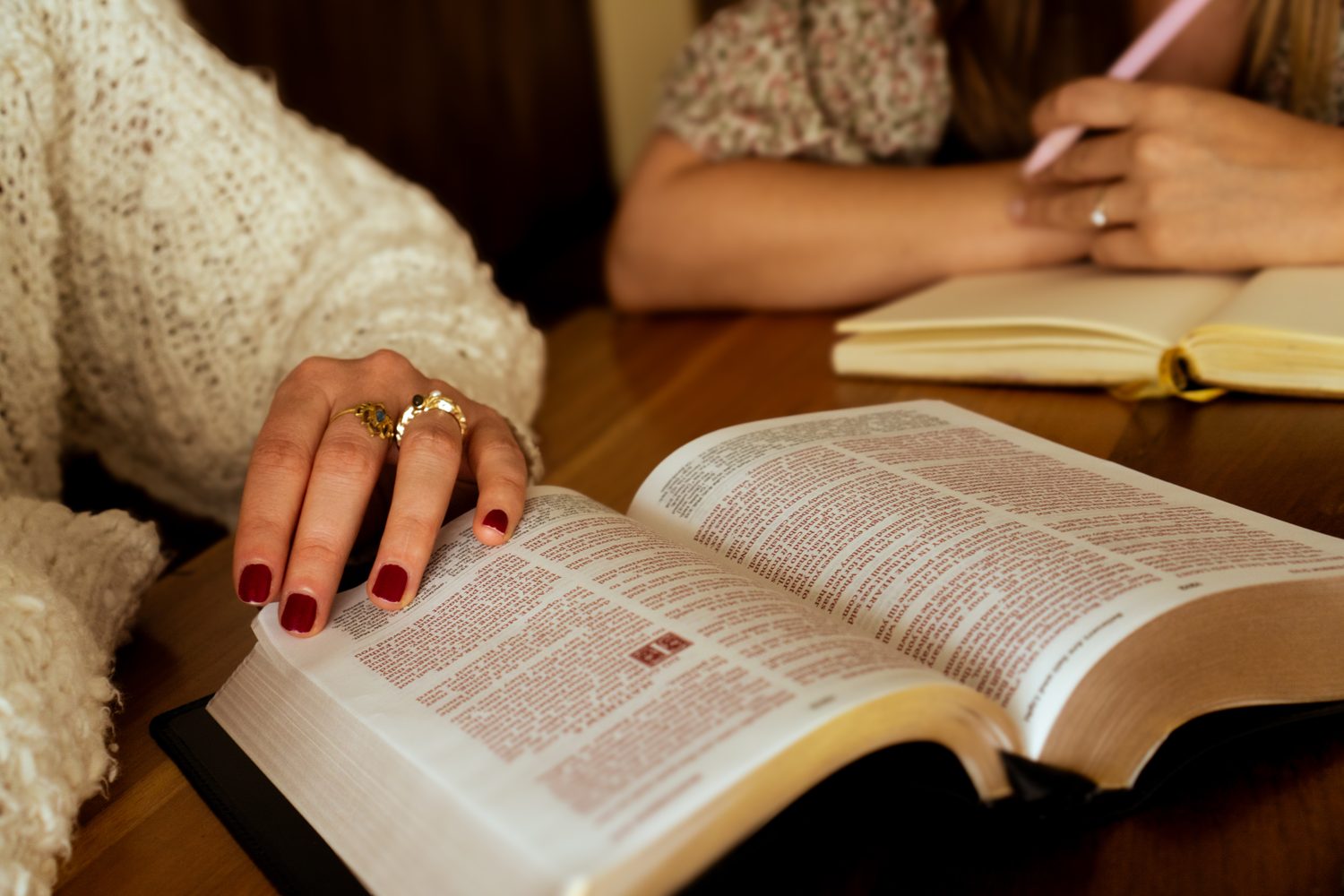 Two women studying an open Bible together at a table