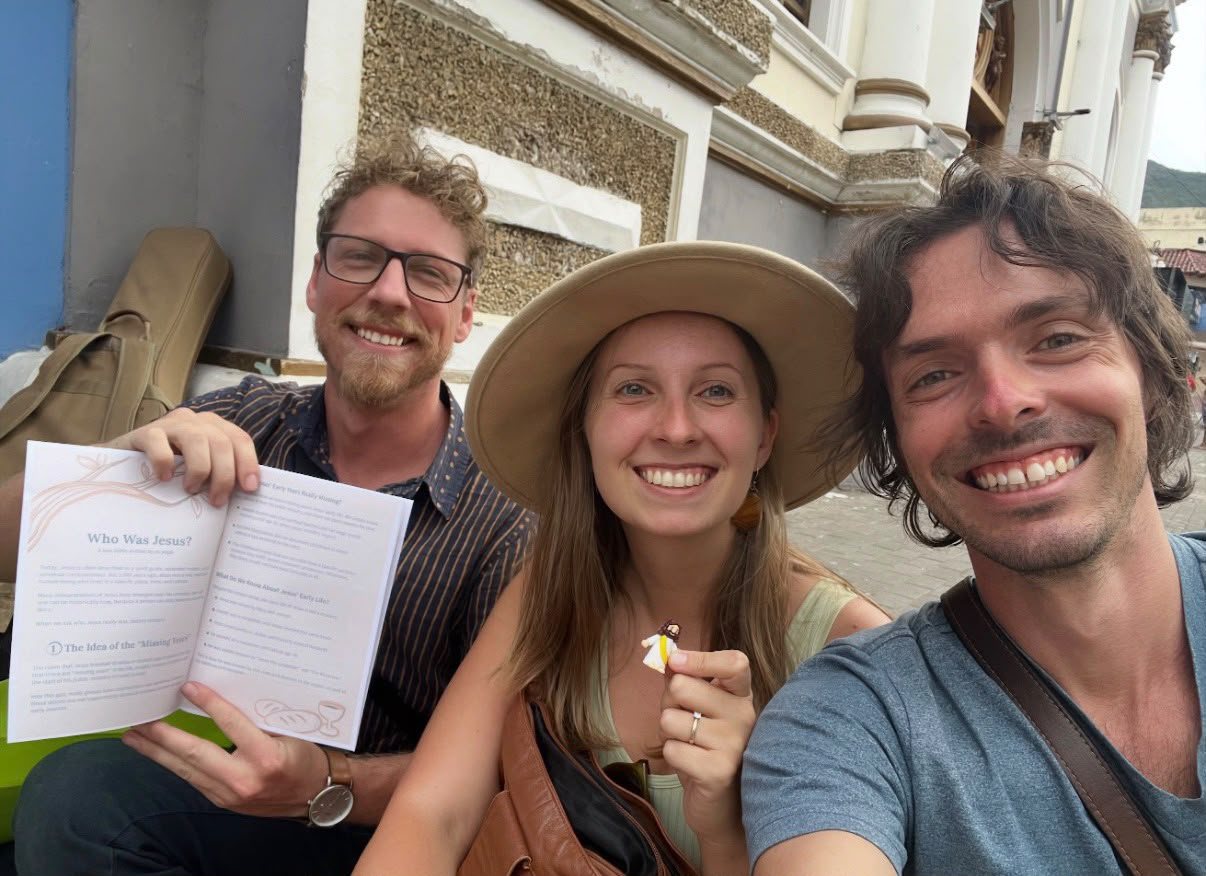 Dylan, Mia and Joe in Guatemala, holding a booklet titled Who Was Jesus?